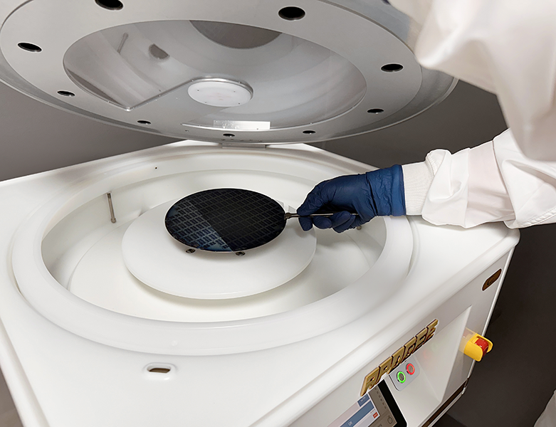 A photo of an operator loading a silicon wafer into a Cee® Apogee® 450 Spin Coater.