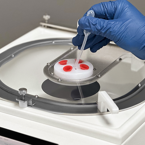 An operator conducting manual dispense through the Cee® Apogee® Benchtop Spin Coater's 5-hole dispense hub.