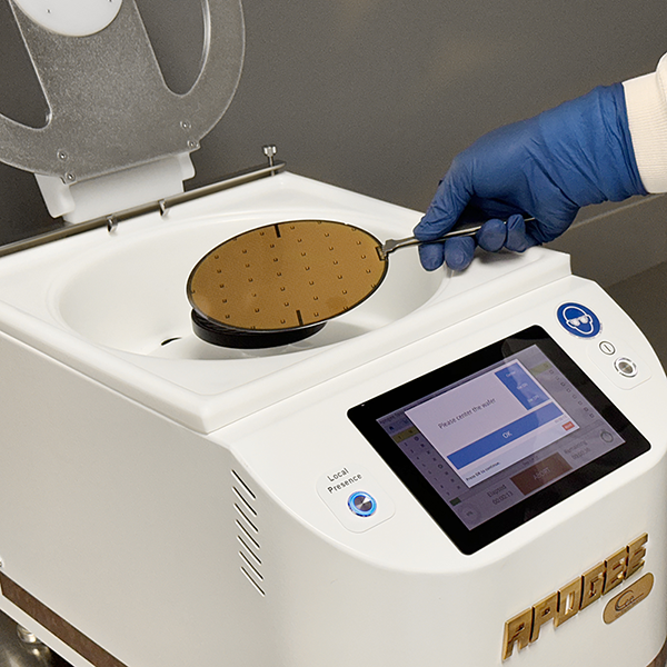 A photo of an operator loading a patterned wafer into a Cee® Apogee Benchtop Spin Coater.